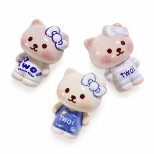 Three mixed-color bear-shaped acrylic beads with bows and printed outfits on a white background
