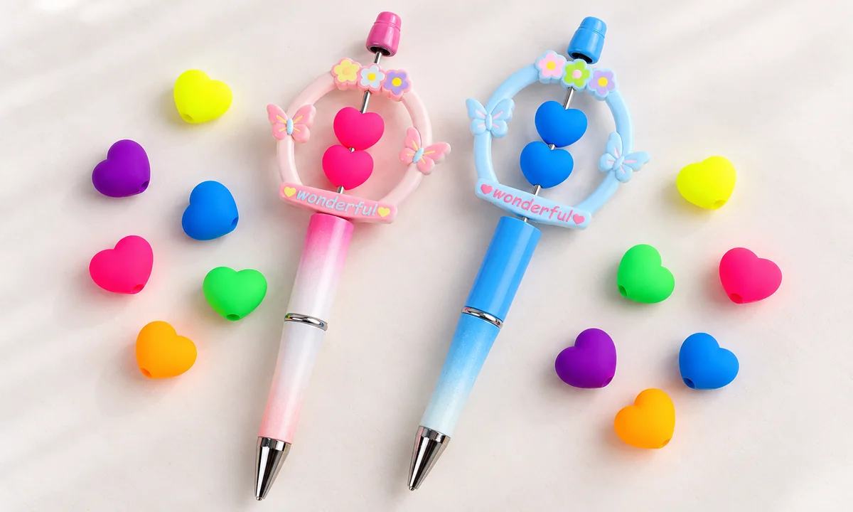 Contas de coração rosa e azul enfiadas em hastes de caneta decorativas, exemplo de projeto; canetas e acessórios não incluídos